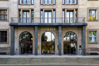 Eingang des Dresdener Rathauses mit drei großen, bogenförmigen Glastüren und goldener Aufschrift 'RATHAUS' über dem mittleren Eingang
